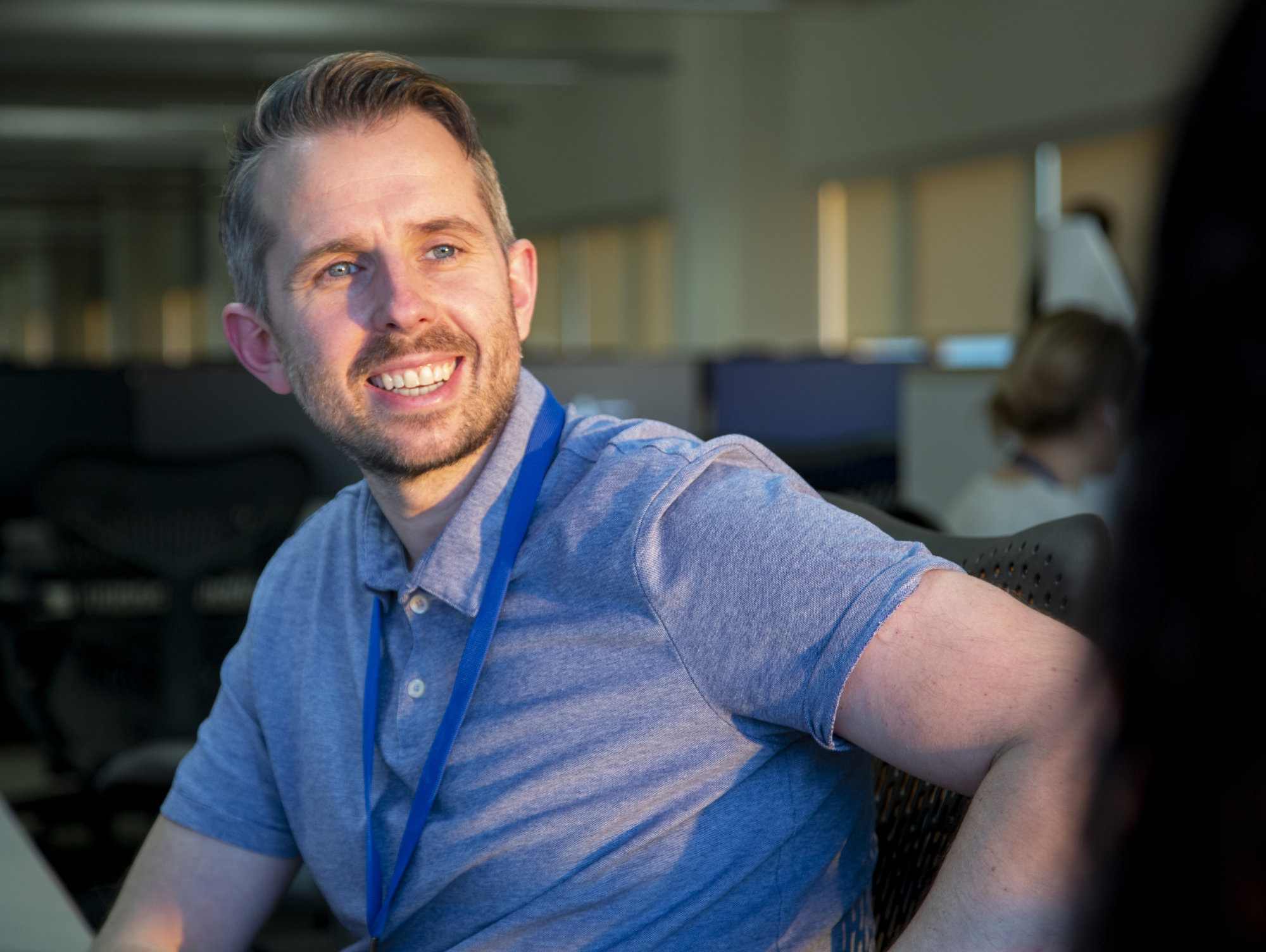 A male office worker smiling at another colleague