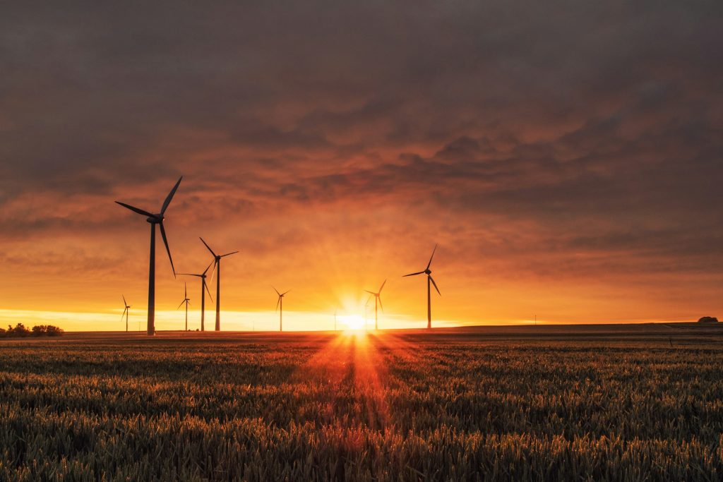 Wind turbines on a large field with the sun setting in the background