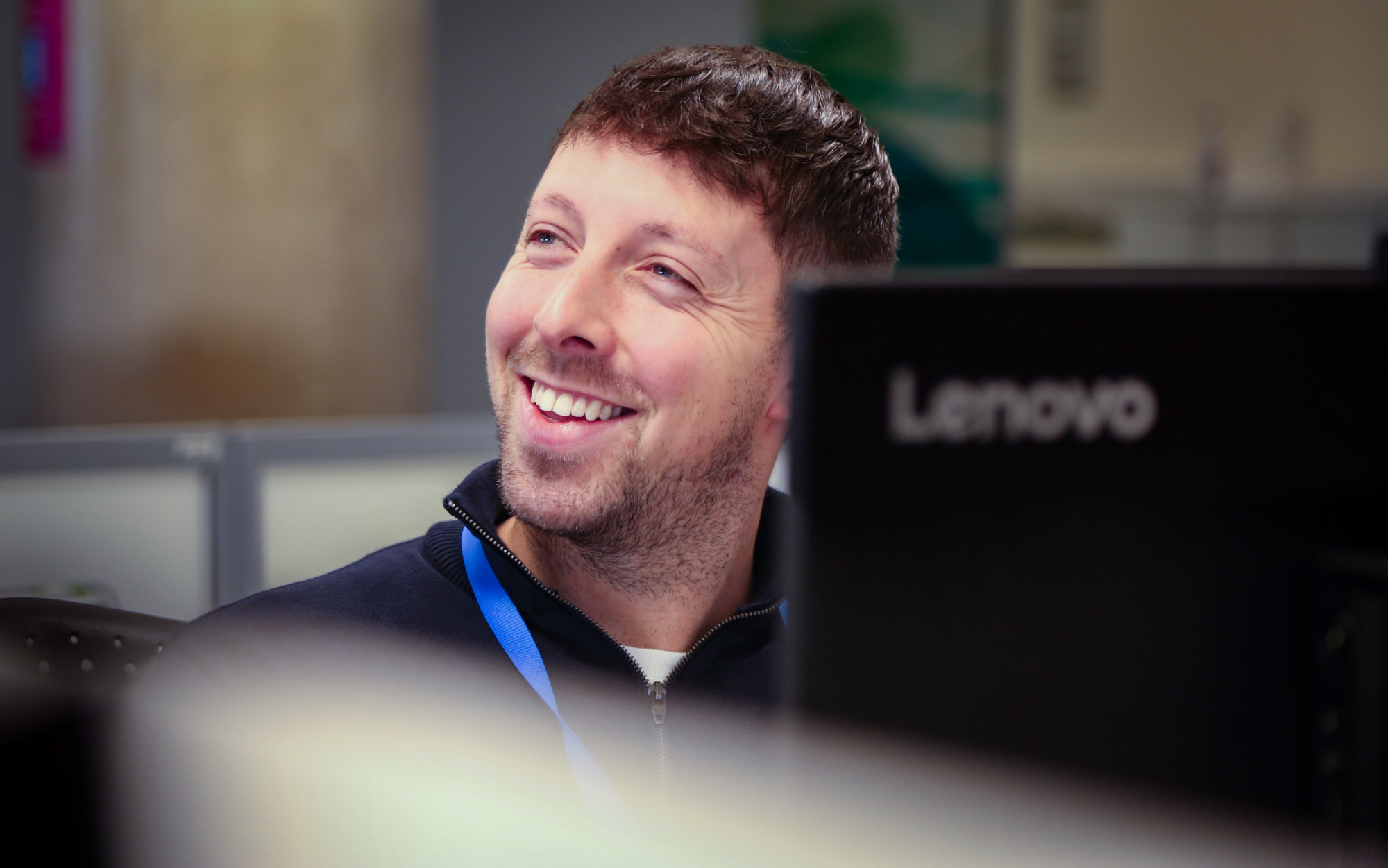 A male office worker smiling at something off camera